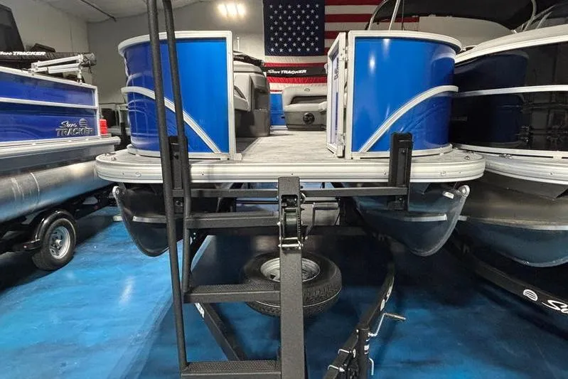 Slide: The Image of 2026 Sun Tracker Party Barge 18 DLX pontoon boat in showroom with American flag backdrop. - 3
