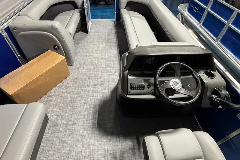 Slide: The Image of 2026 Sun Tracker Party Barge 18 DLX interior with gray seating and steering console. - 9