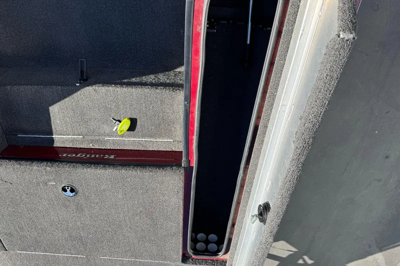 Slide: The Image of 2016 Ranger RT178 boat storage compartment with carpeted interior and fishing rod holders. - 16