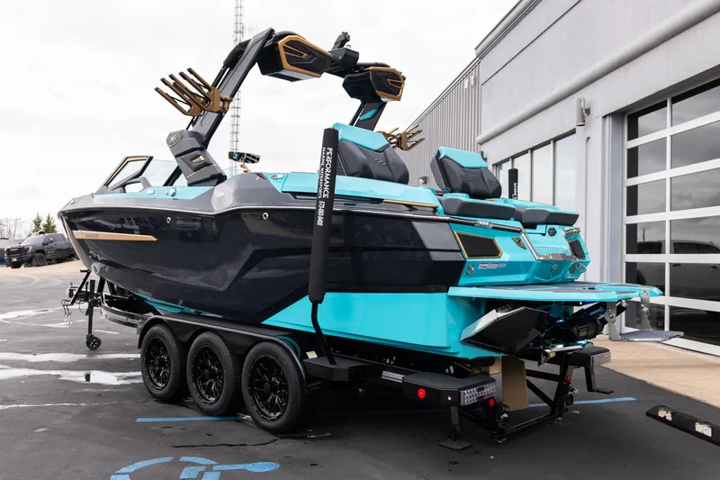 Slide: The Image of 2026 MasterCraft X24 boat on trailer, vibrant blue and black design, parked near a building. - 60