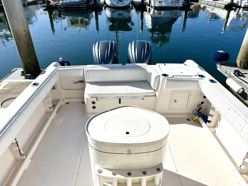 Slide: The Image of 2003 Grady-White Marlin 300 boat interior at marina, featuring seating and twin engines. - 21