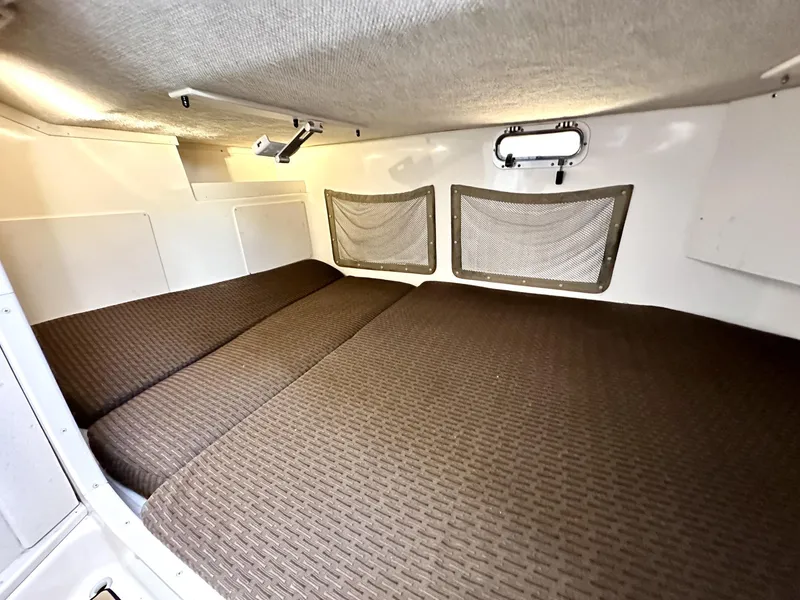 Slide: The Image of 2003 Grady-White Marlin 300 cabin interior with brown bedding and storage nets. - 27