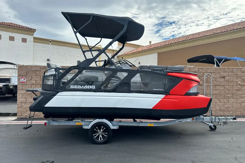 Slide: The Image of 2023 Sea-Doo Switch Cruise 18 on trailer, red and black design, parked outdoors. - 1