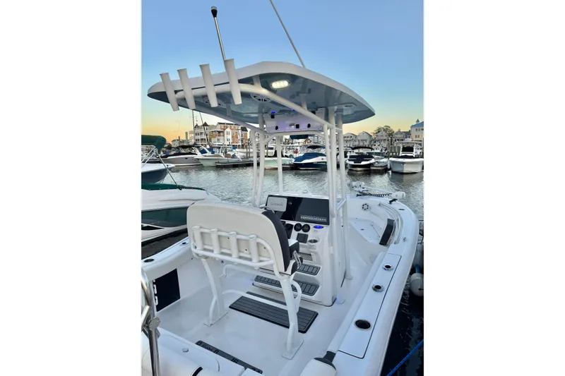Slide: The Image of 2021 Tidewater 210 LXF boat on calm water near coastal buildings at sunset. - 16