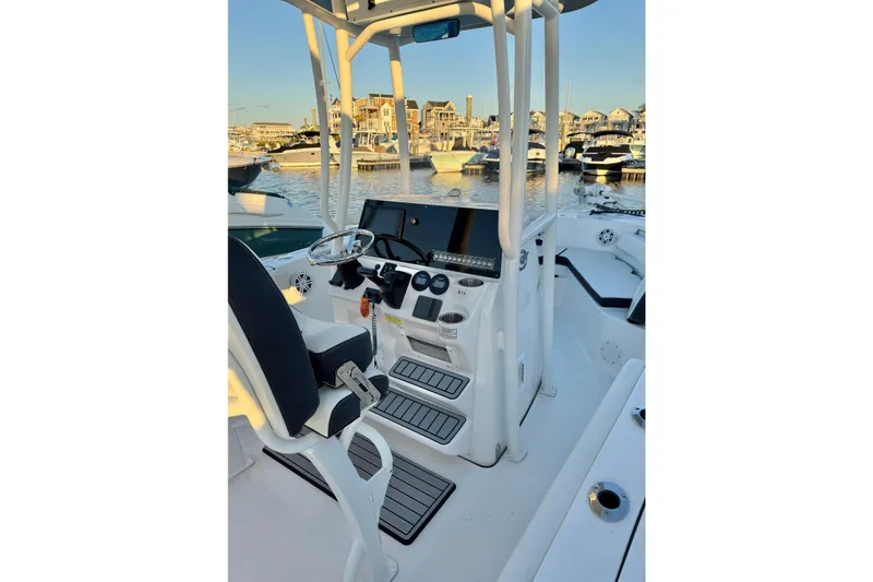Slide: The Image of 2021 Tidewater 210 LXF boat interior with steering console, docked in a marina. - 22