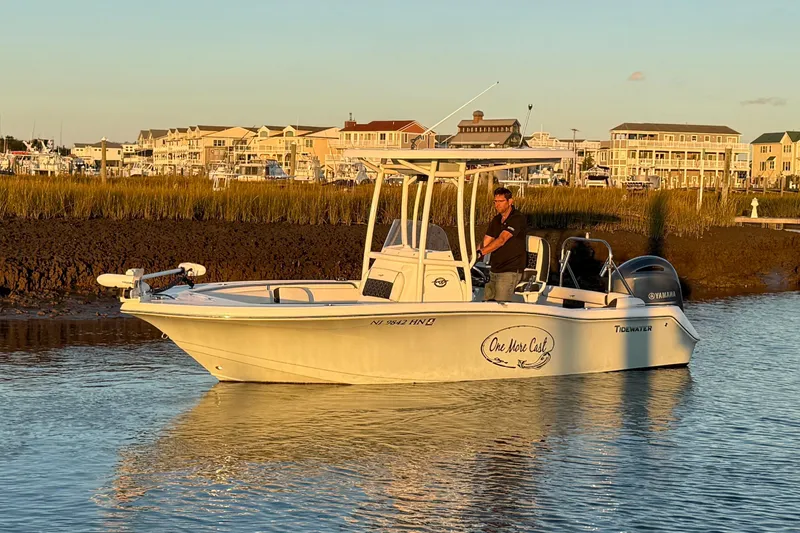 Slide: The Image of 2021 Tidewater 210 LXF boat navigating shallow waters near grassy shoreline. - 11