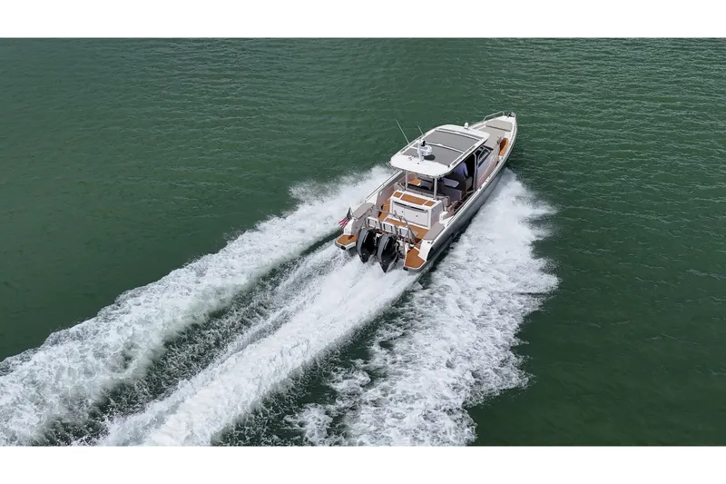 Slide: The Image of 2024 Axopar 37 Sun Top boat cruising on open water, rear view. - 11