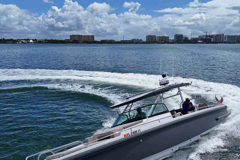 Slide: The Image of 2024 Axopar 37 Sun Top cruising on open water under a cloudy sky. - 13