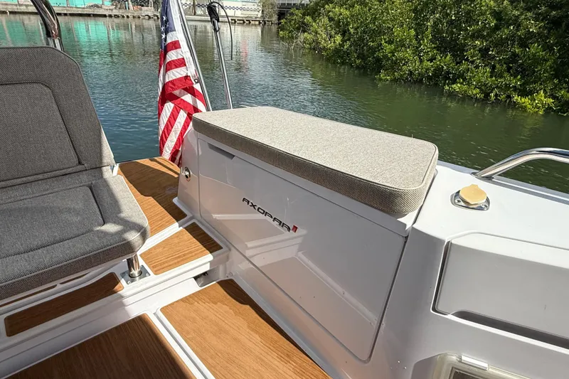 Slide: The Image of 2024 Axopar 37 Sun Top boat interior with cushioned seating and wooden deck. - 17