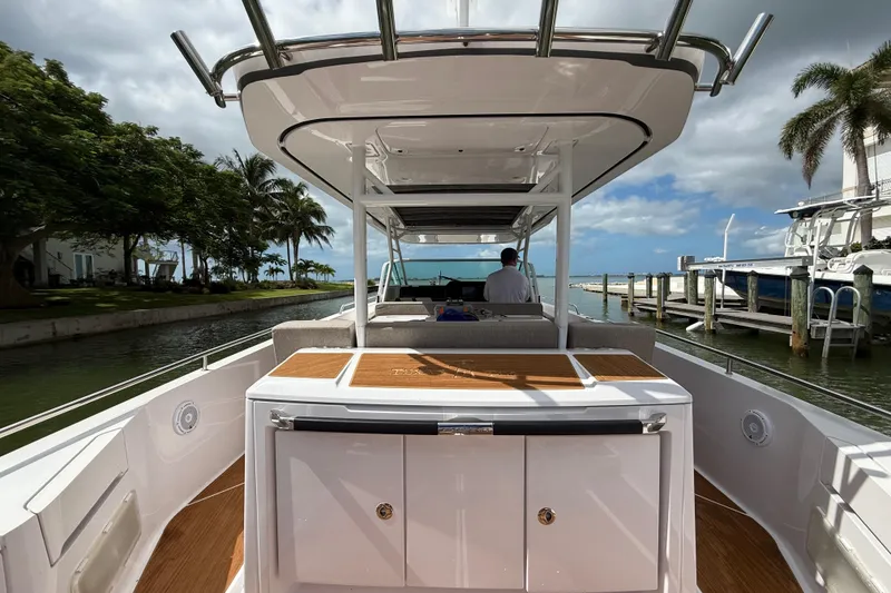 Slide: The Image of 2024 Axopar 37 Sun Top boat with canopy, docked near tropical waterfront homes. - 20