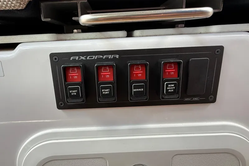 Slide: The Image of 2024 Axopar 37 Sun Top boat seating area with gray cushions and control panel. - 26