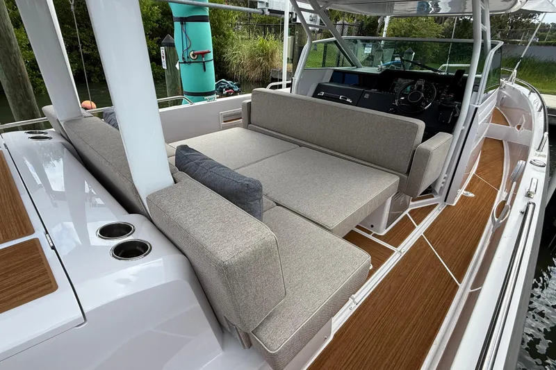 Slide: The Image of 2024 Axopar 37 Sun Top boat interior with cushioned seating and wooden flooring. - 29