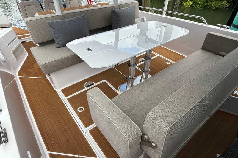 Slide: The Image of 2024 Axopar 37 Sun Top boat interior with gray cushioned seating and wooden flooring. - 31