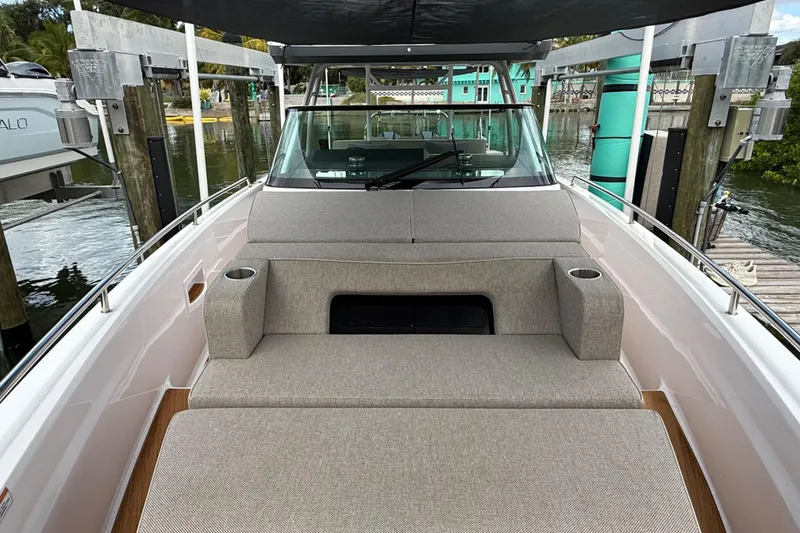 Slide: The Image of 2024 Axopar 37 Sun Top boat with cushioned seating and cup holders, docked by the water. - 51