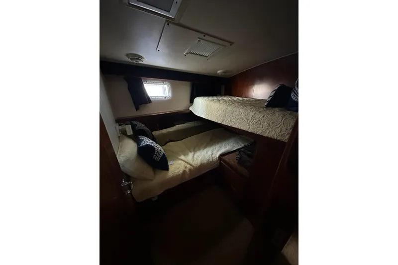 Slide: The Image of Interior of 1988 Hatteras 48 Convertible yacht bedroom with bed, pillows, and wooden cabinetry. - 18