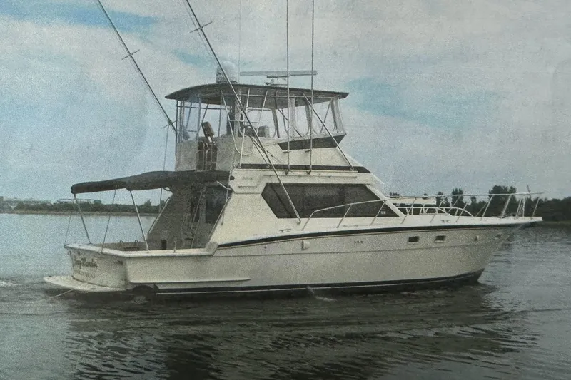 Slide: The Image of 1988 Hatteras 48 Convertible yacht on deck, marina background with boats and buildings. - 50