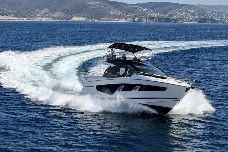 Slide: The Image of 2023 Sunseeker 65 Sport Yacht cruising on open water with scenic coastal backdrop. - 3