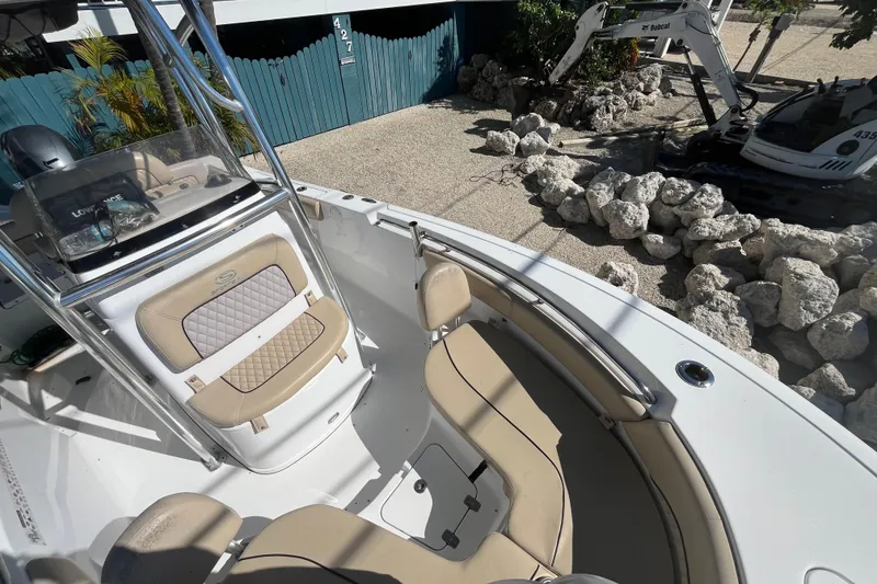 Slide: The Image of 2014 Sportsman Heritage 211 Center Console boat with beige seating, parked near rocks and machinery. - 13