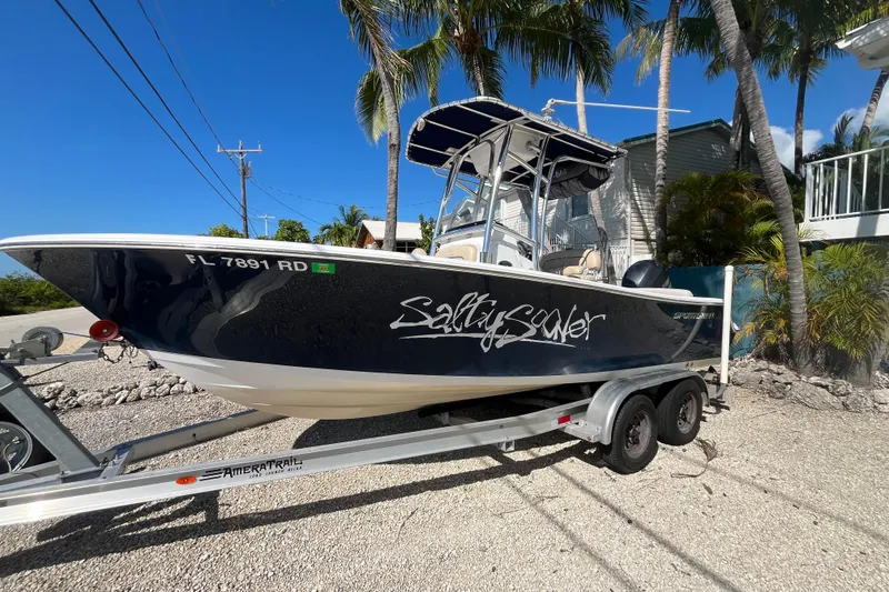 Slide: The Image of 2014 Sportsman Heritage 211 Center Console boat on trailer, parked under palm trees. - 3