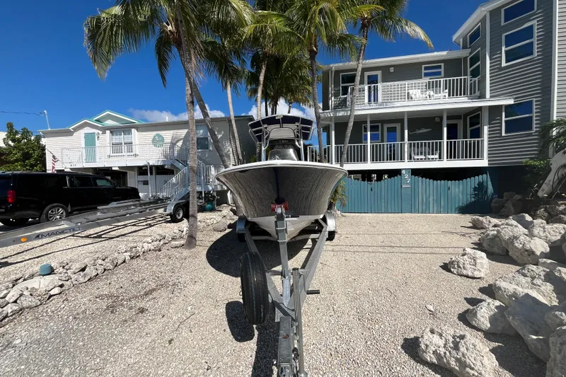 Slide: The Image of 2014 Sportsman Heritage 211 Center Console boat on trailer, parked near coastal homes. - 4