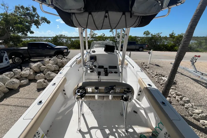 Slide: The Image of 2014 Sportsman Heritage 211 Center Console boat with steering wheel and controls, parked near rocks. - 8