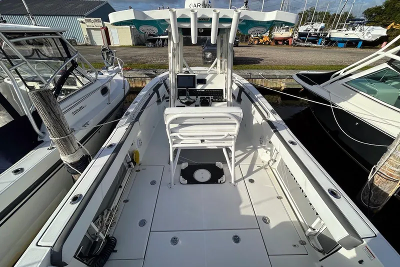 Slide: The Image of 2019 Blackfin 242 CC boat interior with helm, docked alongside other vessels. - 12