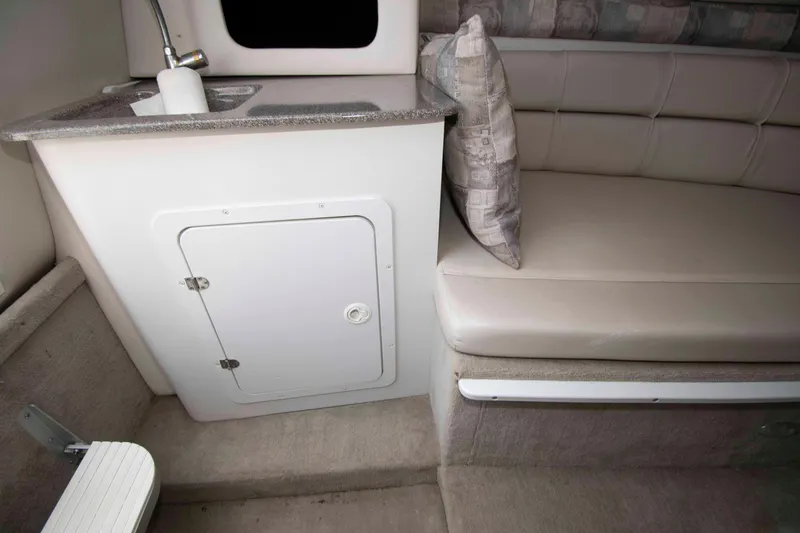Slide: The Image of 2004 Crownline 235 CCR cabin interior with sink, storage, and cushioned seating. - 8