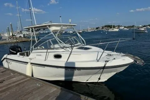 Slide: The Image of 2000 Boston Whaler 23 Conquest boat docked at marina, clear sky, calm water. - 2