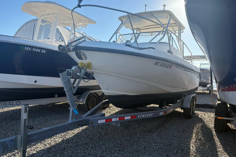 Slide: The Image of 2000 Boston Whaler 23 Conquest boat on trailer, parked between other boats. - 4