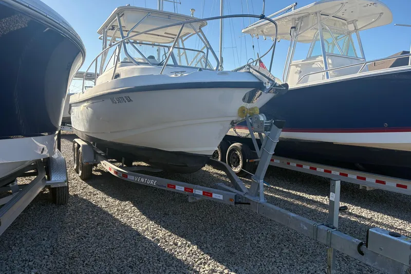 Slide: The Image of 2000 Boston Whaler 23 Conquest boat on trailer, parked between other boats. - 5