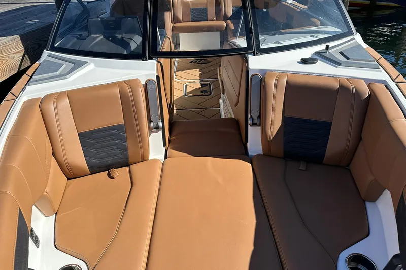 Slide: The Image of 2024 Malibu Wakesetter 25 LSV interior with tan and black seating, docked by water. - 16