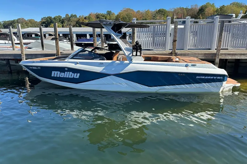 Slide: The Image of 2024 Malibu Wakesetter 25 LSV boat docked on a sunny day. - 2
