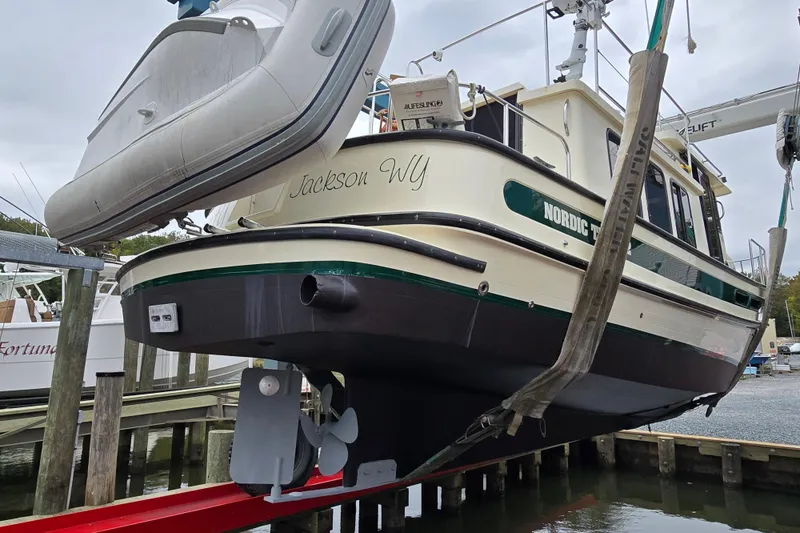 Slide: The Image of 2001 Nordic Tug 32 with Seakeeper, lifted at dock, featuring green and white design. - 52