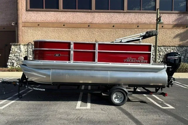 The Image of 2026 Sun Tracker Party Barge 16 DLX pontoon boat on trailer in parking lot. - 0
