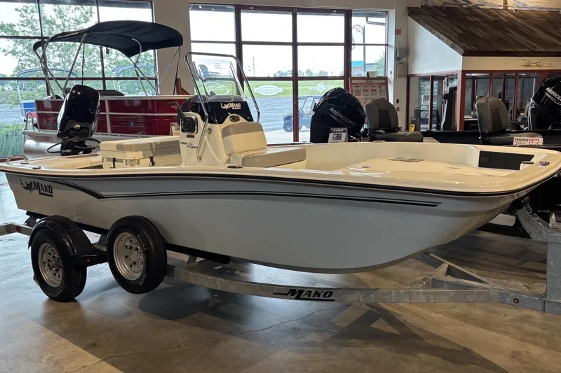 The Image of 2026 Mako Pro Skiff 15 CC boat on trailer in showroom setting. - 0