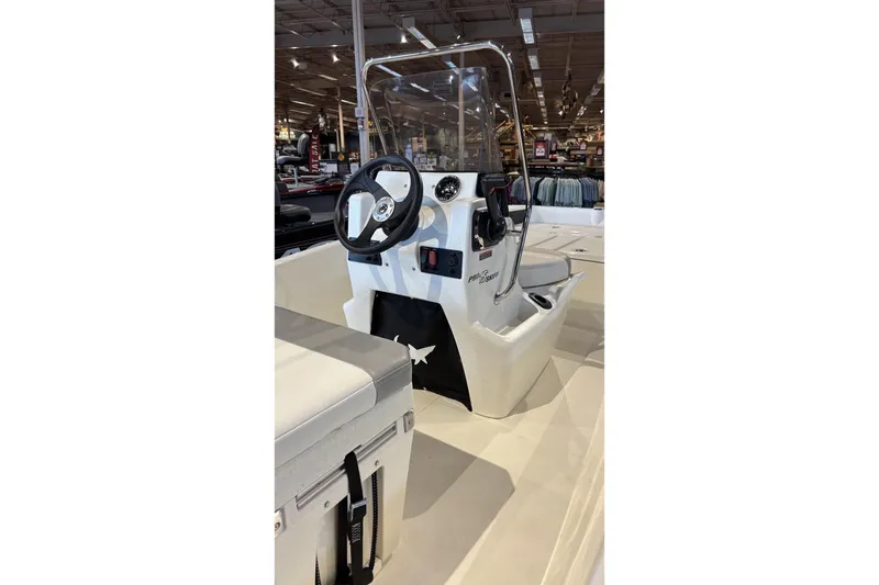 Slide: The Image of 2026 Mako Pro Skiff 15 CC boat interior with steering console in showroom. - 2