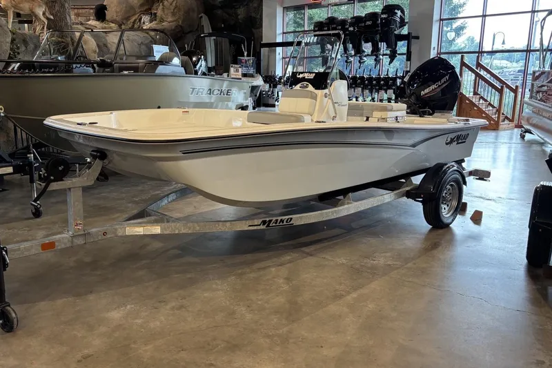 Slide: The Image of 2026 Mako Pro Skiff 15 CC boat on trailer in showroom setting. - 1