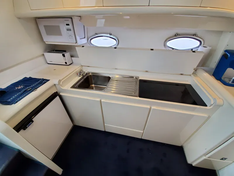 Slide: The Image of Compact kitchen in a 1993 Giorgi 46 yacht with sink, microwave, and portholes. - 12