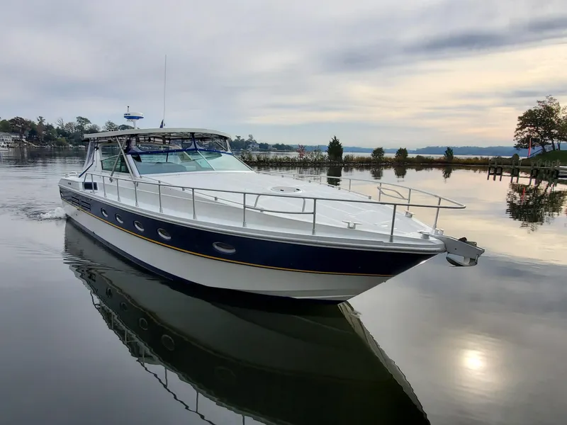 Slide: The Image of Giorgi 46 yacht from 1993 on calm water, reflecting serene sky and shoreline. - 15