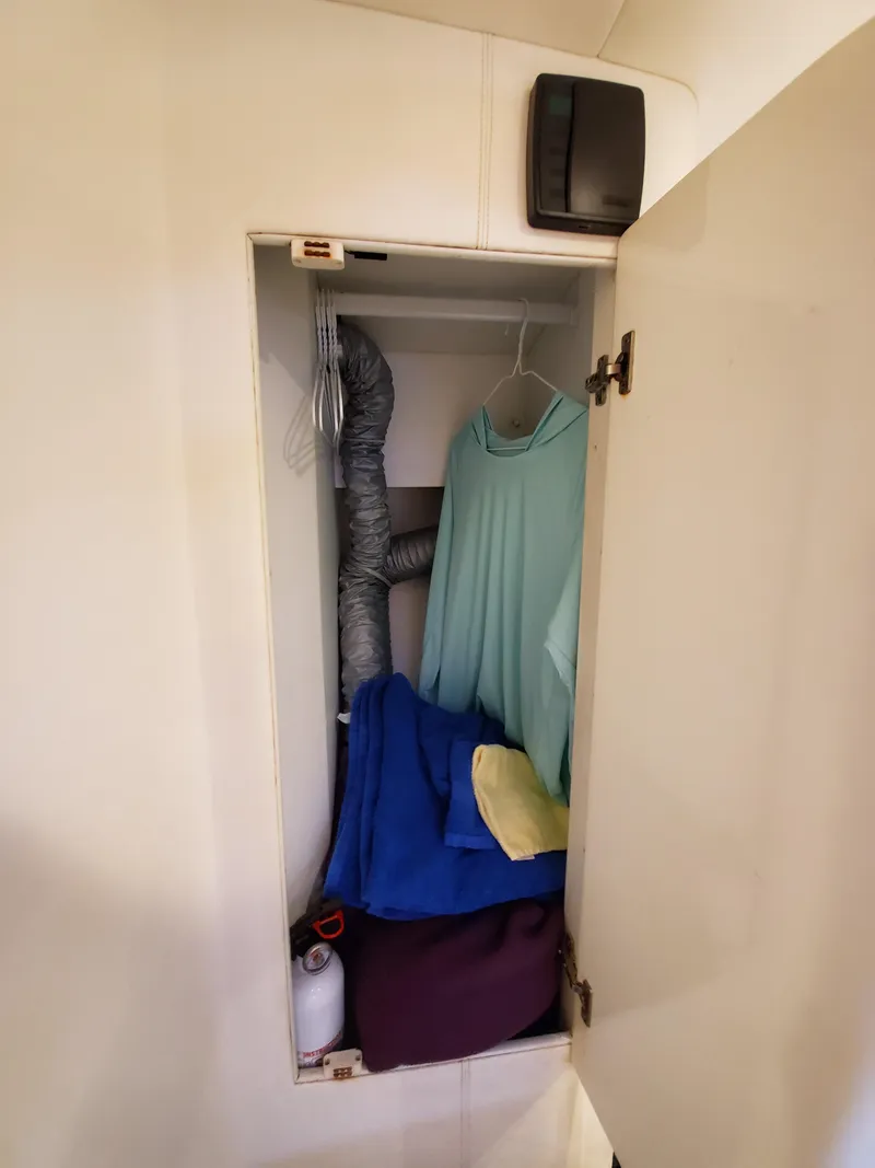 Slide: The Image of Small closet with clothes, storage items, and ventilation hose in a Giorgi 46, 1993 model. - 23