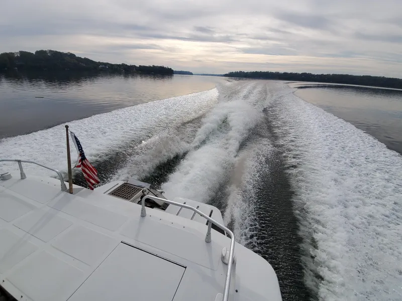 Slide: The Image of A 1993 Giorgi 46 boat cruising on a calm lake, leaving a foamy wake. - 4
