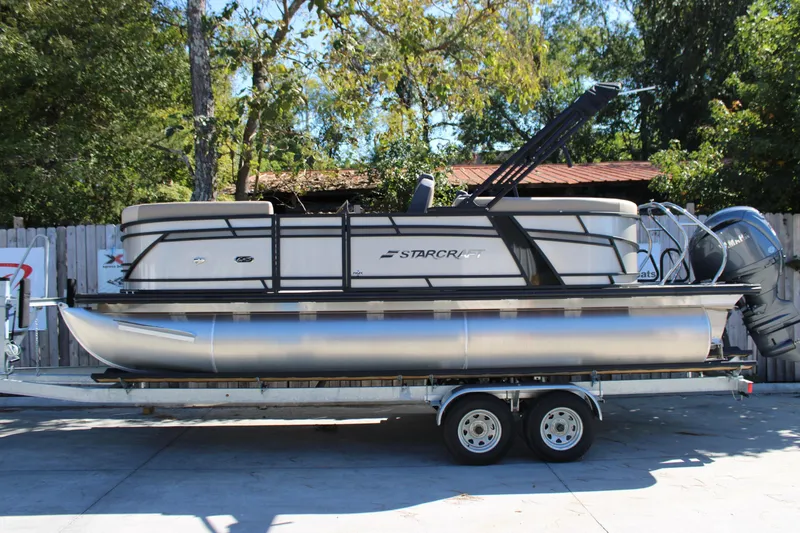 The Image of 2026 Starcraft EXS 1 pontoon boat on trailer, parked outdoors. - 1
