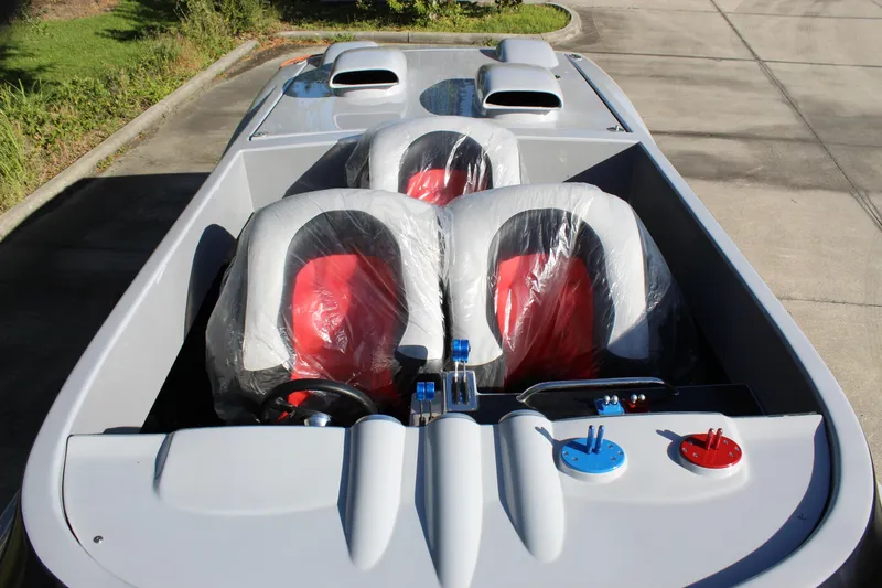 Slide: The Image of 2007 Chaudron 41 SS boat interior with red and gray seats, parked on pavement. - 34