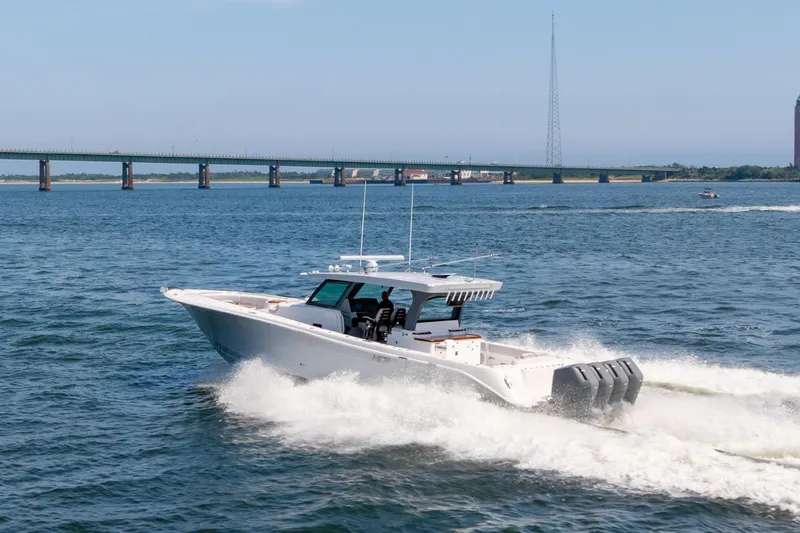 Slide: The Image of 2026 HCB 48 Campeon boat cruising on open water near a bridge. - 10