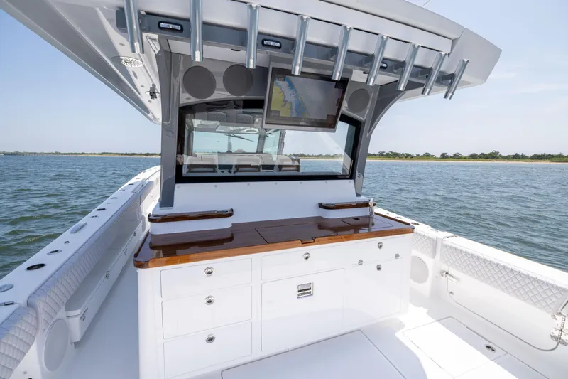 Slide: The Image of 2026 HCB 48 Campeon boat interior with navigation screen and storage, on calm water. - 24