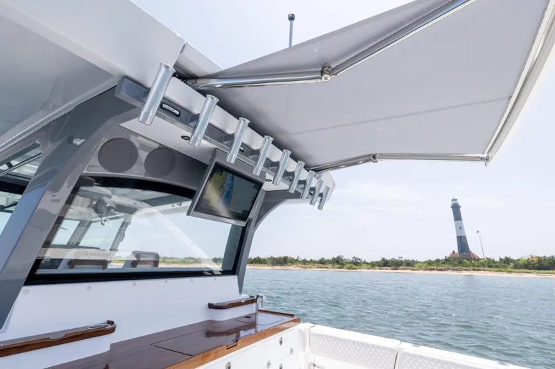 Slide: The Image of 2026 HCB 48 Campeon boat with rod holders, near a lighthouse on a sunny day. - 26