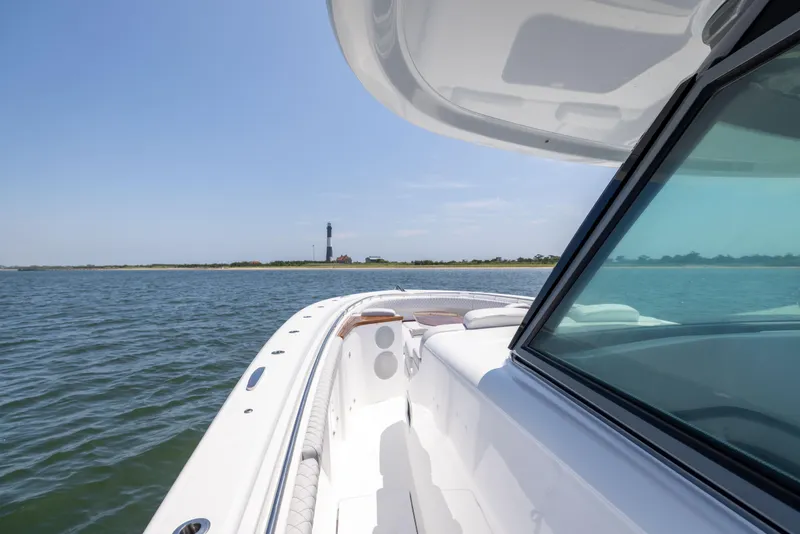 Slide: The Image of 2026 HCB 48 Campeon boat cruising near a lighthouse on a sunny day. - 28
