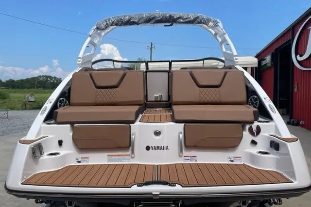 Slide: The Image of 2025 Yamaha Boats 252S with brown seating and sleek design, docked outdoors. - 3