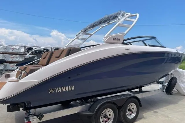 Slide: The Image of 2025 Yamaha Boats 252S on trailer, sleek design, blue and white exterior, sunny day. - 4