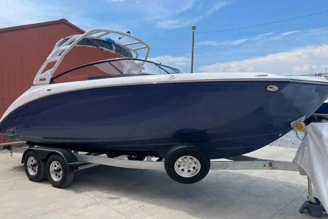 Slide: The Image of 2025 Yamaha Boats 252S on trailer, blue hull, parked outdoors. - 5